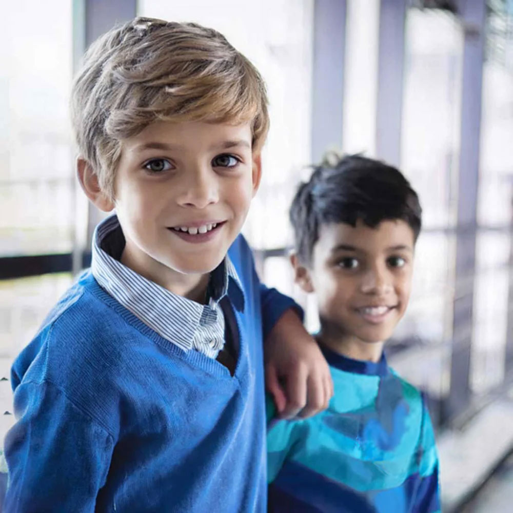 Zwei Jungen mit blauen Pullovern im Flur der Schule
